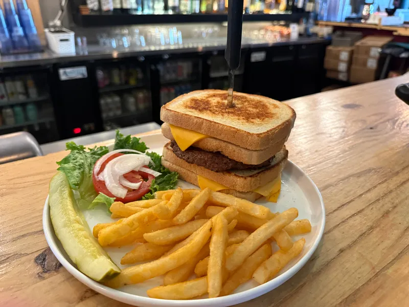 Grilled-cheese-bun burger with crinkle fries, a pickle spear, and lettuce, tomato and onion