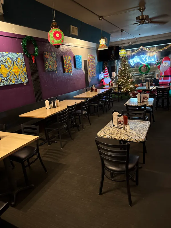 The dining room decorated for the holidays with a lit Christmas tree, wreaths, and local artwork